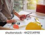 Engineer builder using mobile phone and walkie talkie, giving instructions at a construction site
