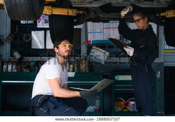 Engineer car\
mechanic under checking under the car by see detail in note book on\
hand for maintenance and fixed\
it.