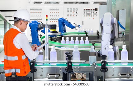 Engineer checking automated robotics in drinks production plant of factory - Powered by Shutterstock