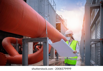 Engineer Checking Blueprint Of Industry Cooling Tower Air Conditioner Is Water Cooling Tower Air Chiller HVAC Of Large Industrial Building To Control Air System ,wearing Mask For Protect Pollution.