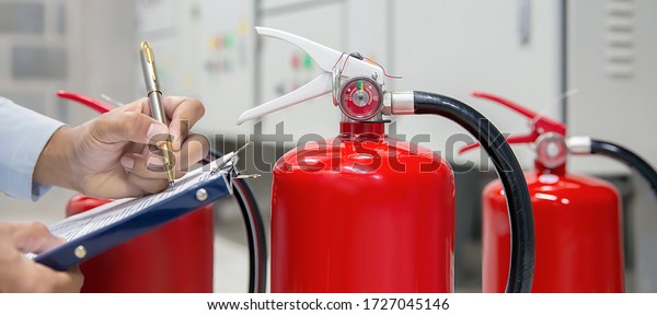 Engineer are checking and inspection a fire\
extinguishers tank in the fire control room for safety training and\
fire prevention.