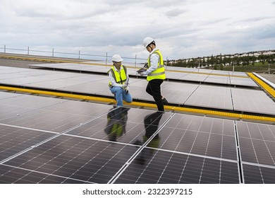 Engineer checking installation of solar panels installed on factory roof, checking installation of solar panels. Asian engineer records inspection data on tablet, supervising solar panel installation.