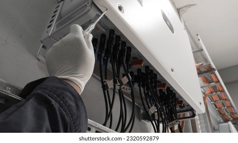 An engineer is checking the leakage current on a solar panel inverter using a test pen.
