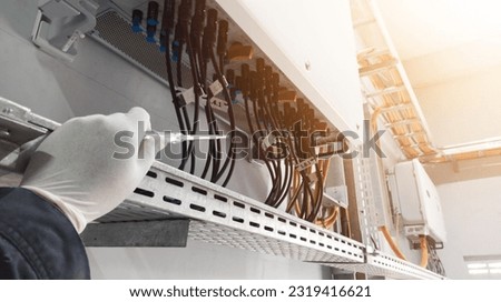 An engineer is checking the leakage current on a solar panel inverter using a test pen.