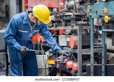 engineer checking metal component at machine receptacle in factory 