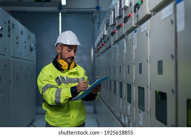 Engineer checking and monitoring the electrical system in the control room. Worker checking and inspecting at switchgear panel.