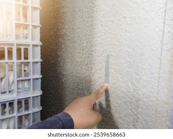 An engineer is checking the thickness of the feather dust on the hatching machine using his index finger.