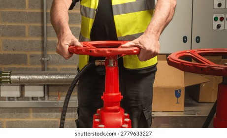 Engineer checking water supply pump on red valve for sprinkler fire protection system. Close up of engineers hands working on a sprinkler fire suppression system. Industrial fire prevention equipment.