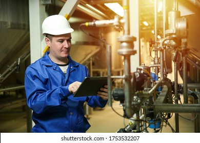 Engineer Checks The Operation Of Equipment In The Factory Workshop. Food Factory Worker Man Is Holding A Tablet At Work. 