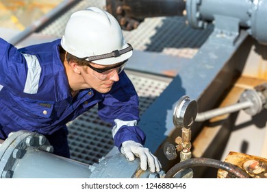 The engineer checks the pressure in the pipe of the cargo system of a oil tanker.