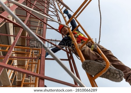 Engineer climbing construction scaffold with safety gear contributing to building project in urban environment