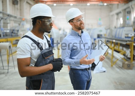 An engineer communicates with a worker on a production line.