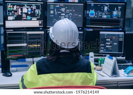 Engineer computer worker on High-performance computers with a lot of monitor in large factory,Control the operation of large machines,Write a program to run the robot,Programmer working with serious
