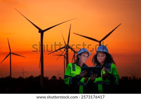 Engineer  concentration table integration of technology and renewable energy management wind farm during sunset or sunrise silhouetted environmental sustainability cleaner energy solutions concept.