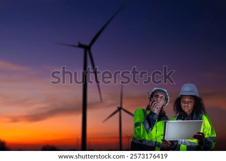 Engineer  concentration table integration of technology and renewable energy management wind farm during sunset or sunrise silhouetted environmental sustainability cleaner energy solutions concept.