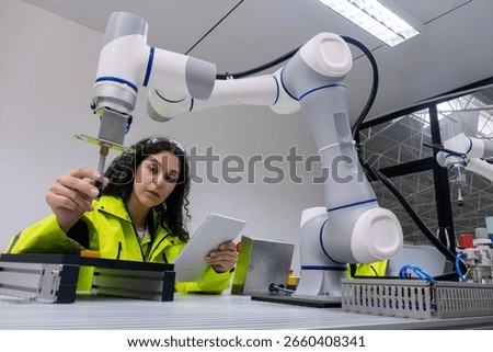 Engineer conducts precision assembly using robotic arm in modern manufacturing facility