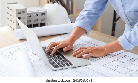 Engineer and construction concept. Engineer technician using laptop to drawing design building project on blueprints and analyzing of project types. Interior design and decoration ideas. Real estate - Powered by Shutterstock