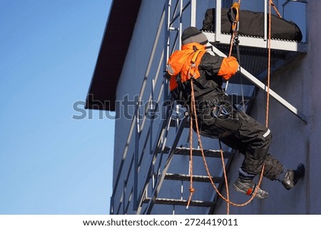 Engineer, construction worker. Man in uniform. Rock climber, arborist. Industrial climber. Working at height. Rescuer, firefighter, dangerous occupation, ropes, carabiners. Industrial climber at work. High-altitude work, dexterous stunt, circus performer, virtuoso, stuntman, dangerous profession. Extreme sportsman                             