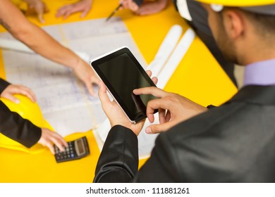 Engineer with construction workers in architecture working on electronic tablet