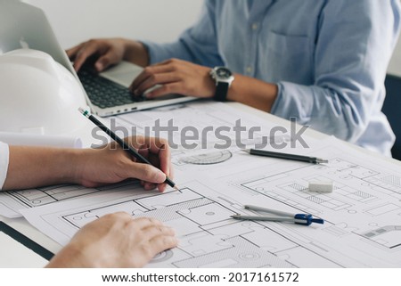 Engineer constuction and interior team dissussing in the office. and angineer working drawing on blueprint meeting for project working with a partner on model building plans at table in the office.