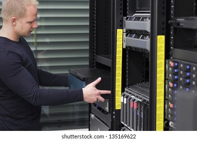 It engineer / consultant install / inserts a router / switch in a rack. Shot in a data center.