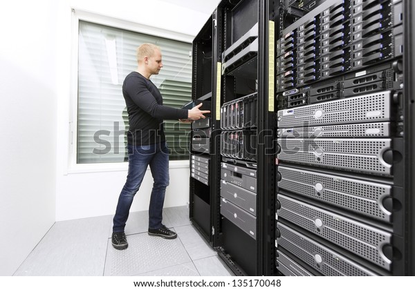 It engineer\
/ consultant wokring and install / inserts a router / switch in a\
data rack. Shot in a data\
center.