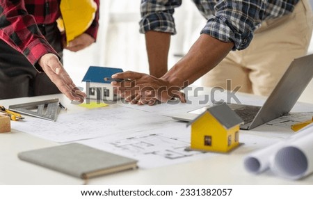 Engineer and contractor planning projects together at desk with blueprints.