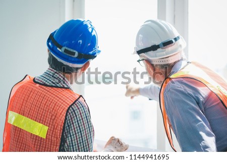 Engineer and contractor team pointing and looking out of window in meeting at construction site, Teamwork concept