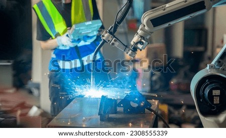Engineer control robot arm machine welding steel, worker using forcing welding control screen which for precision welding control. Worker control automation welding robot in hi tech heavy factory