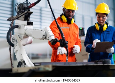technische Zusammenarbeit zwischen männlichen und weiblichen Techniker Kontrolle Relais Roboter-Arm-System-Schweißung mit Tablet-Laptop zur Kontrolle der Qualität Betrieb Arbeitsprozess schwere Industrie 4.0 Fabrik