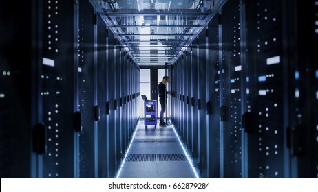 IT Engineer With Crash Cart Puts Hard Drives into Open Rack Server Cabinet. He's Working in Big Data Center. - Powered by Shutterstock