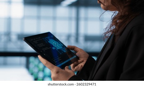 Engineer in data center with tablet integrating AI driven automation tools. Worker ensuring continuous uptime of server room using artificial intelligence, managing data flows, camera A