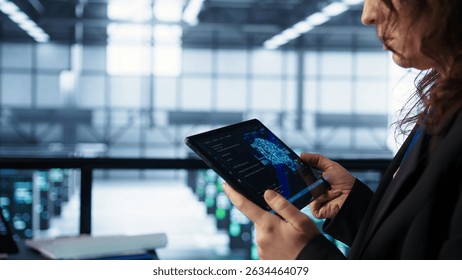 Engineer in data center with tablet integrating AI driven automation tools. Worker ensuring continuous uptime of server room using artificial intelligence, managing data flows, camera B