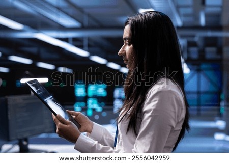 Engineer in data center updating systems to keeps performance up and protect servers from easily exploitable software vulnerabilities. Employee looking for errors causing servers to slow down using