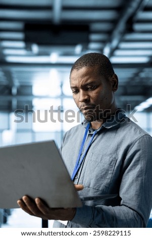 Engineer in data center using laptop, adjusting power management settings, verifying compliance requirements, optimizing resource utilization, maintaining stable infrastructure