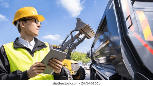 Engineer with a digital tablet on the background of construction machines.