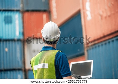 Engineer dock worker in protective safety jumpsuit uniform and with hardhat and use laptop computer at cargo container shipping warehouse. transportation import,export logistic industrial