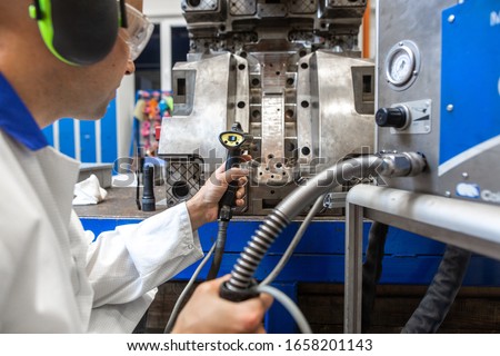 Engineer doing maintenance on a injection mold for plastic components, industrial and automotive concept
