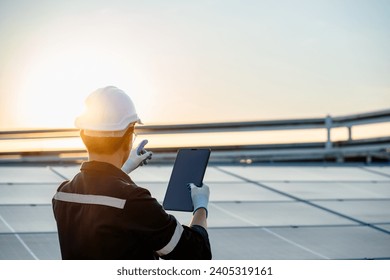 Engineer electrician using a digital tablet to check solar panels on the roof, clean energy power nature, photovoltaic systems, the energy produced by the sun, sustainable business concept.