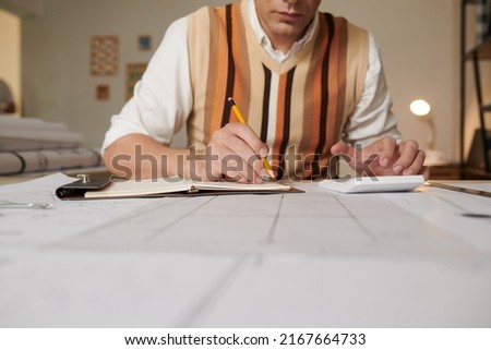 Engineer estimating project time and cost when working on blueprint for client
