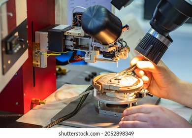 An engineer examines microchip. Microchip transistor in microscope. Engineer's hands next to microscope. Testing of microprocessors in laboratory. Computer chip testing. PCB research.