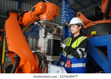 Engineer explaining colleague over robotic arm in factory. Robotic Arm engineer check on equipment in its with software  of an Artificial Intelligence Computer Processor Unit.