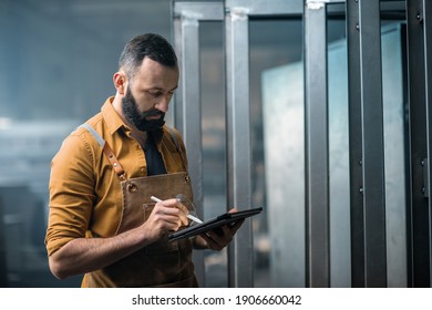 Engineer or factory worker using digital technology in the production of metal products, using a digital tablet at the plant. High quality photo