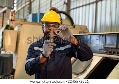 Engineer or factory worker wearing safety uniform under measuring a metal part with a digital vernier caliper  is quality control of parts machined on  lathe structure.