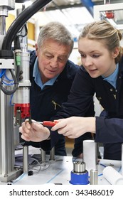 Engineer And Female Apprentice Working On Machinery In Factory