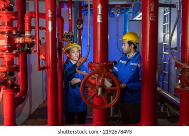 An engineer in the fire protection pump room talking with walkie talkie checking and operate trouble shooting defective spray nozzle head valve at the red pipeline
				