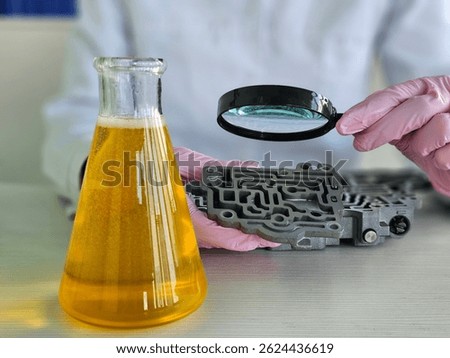 Engineer from flask yellow liquid into automatic transmission in chemical laboratory closeup. Testing lubricants for automotive parts
