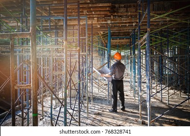 Engineer or foreman with blueprint in building construction site