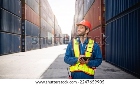 Engineer or foreman checking inventory or task details at container yard warehouse while wearing PPE and holding tablet., Logistics concept inside the shipping, import, and export industries.