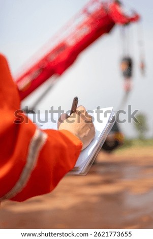 An engineer or foreman is checking on safety checklist form of lifting crane at the drilling rig work site. Industrial safe working concent, close-up and selective focus.